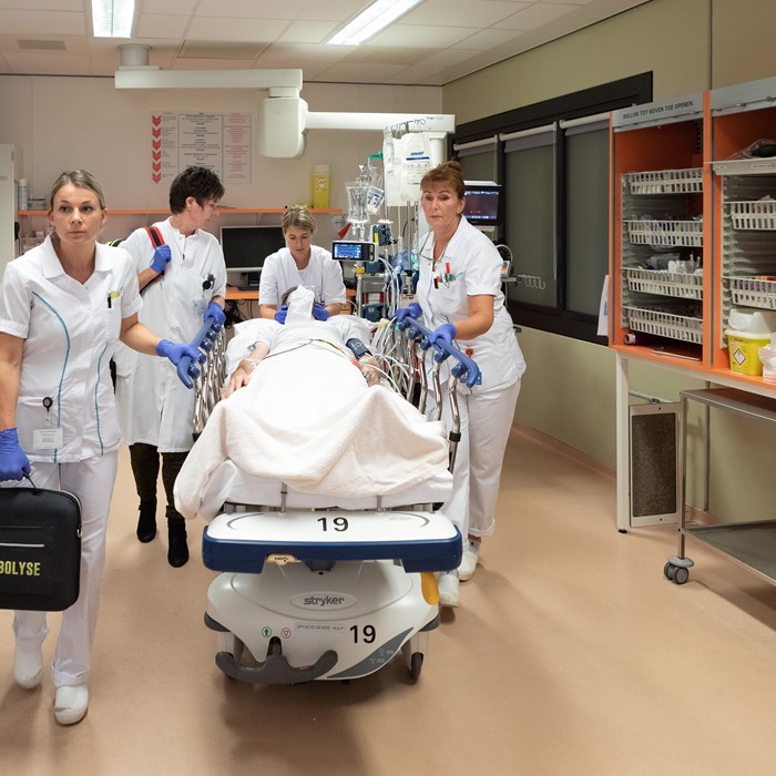 Artsen en verpleegkundigen verplaatsen een patiënt in bed op de Spoedeisende Hulp. 