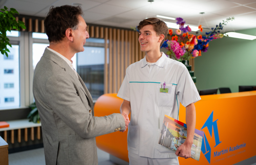 Directeur van de Martini Academie schudt de hand van een stagiair verpleegkundige
